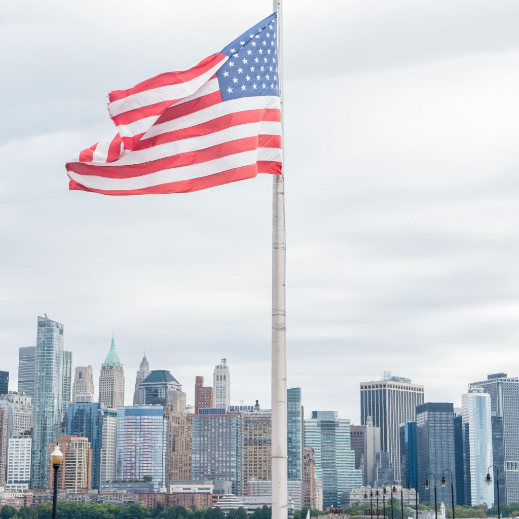 Majestic American flag waves proudly with New York City skyline in the background.